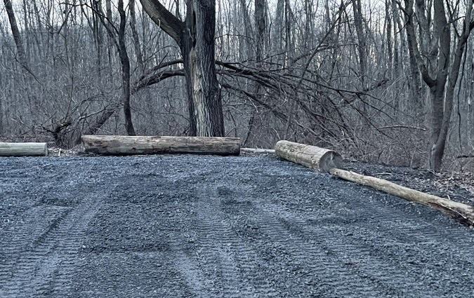 a gravel parking lot with logs around the perimeter.