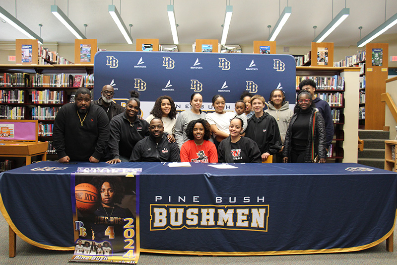 A high school  age young woman sits at a table surrounded by friends and family. The table cloth says Pine Bush Bushman