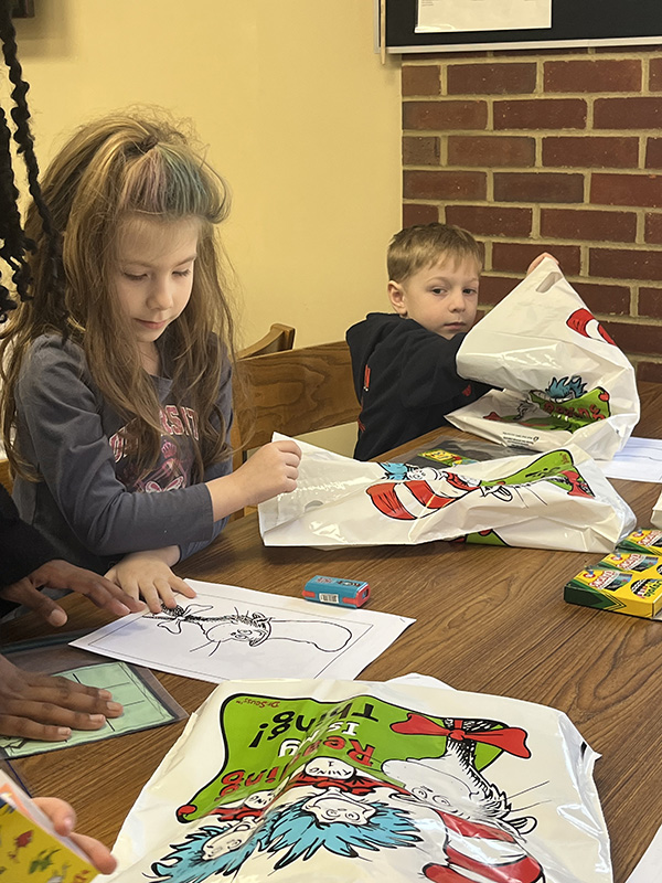 Elementary students color pictures of the cat in the hat.