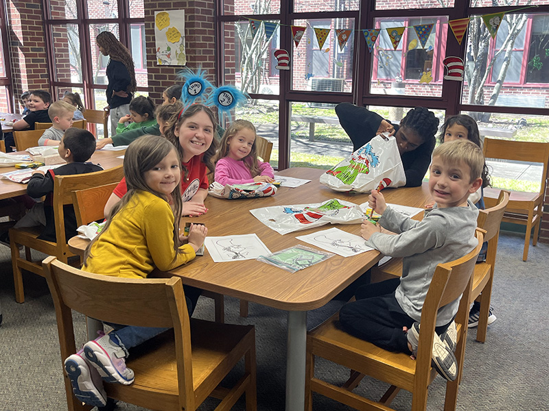 A group of kindergarten students sit at a table doing crafts.