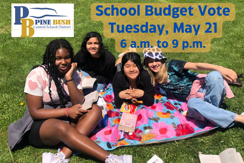 A photo of four middle school girls sitting on a blanket in the grass with books around them. Above them says School Budget Vote Tuesday, May 21 6 a.m. to 9 p.m.