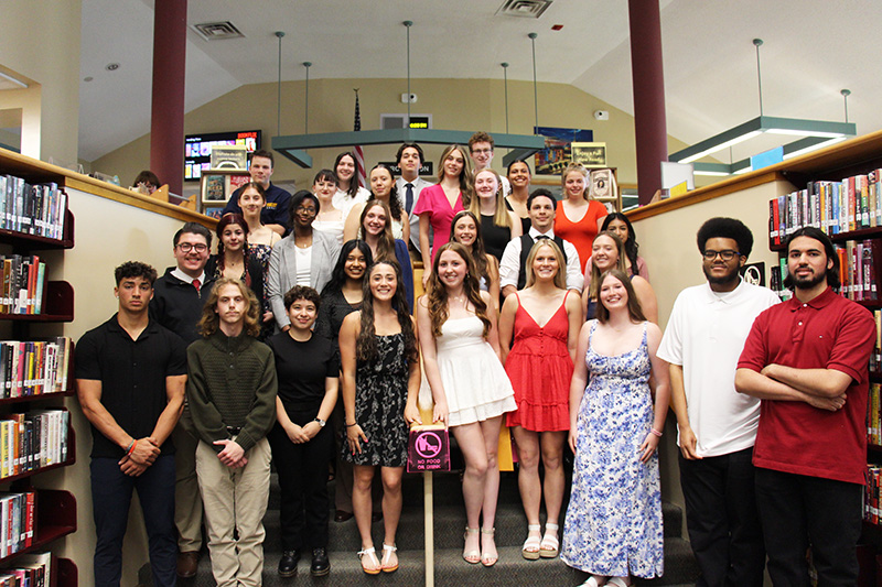 A group of 29 high school seniors stand in rows on steps. They are all smiling