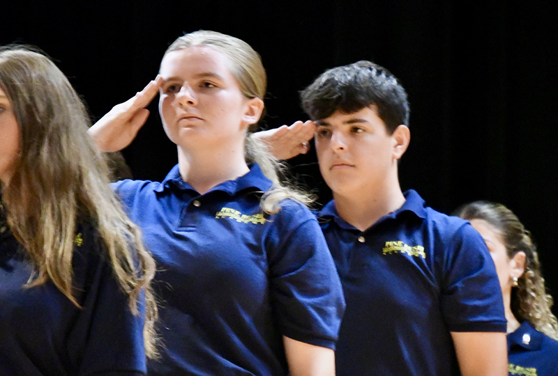 A high school girl and boy salute.