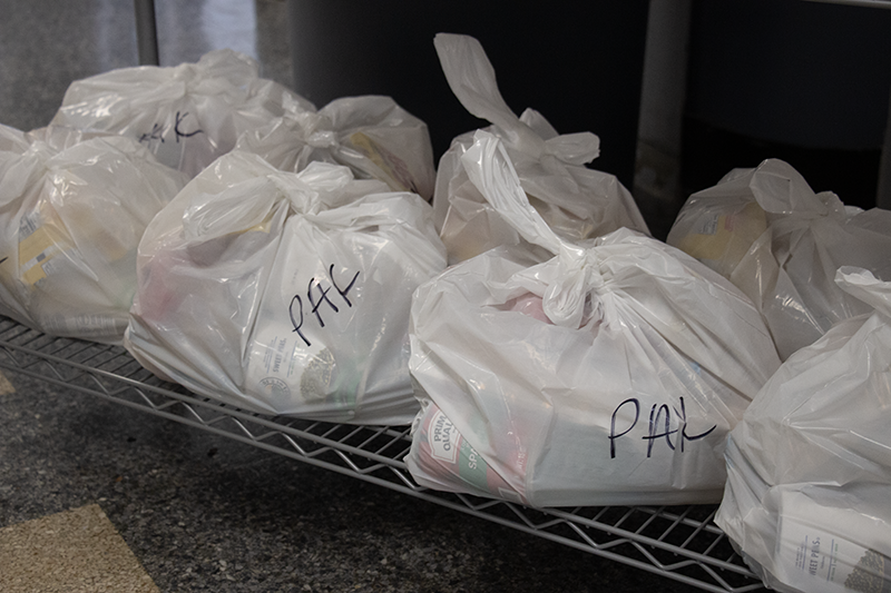Large white plastic bags tied and sitting on a shelf. They say PAK on them.
