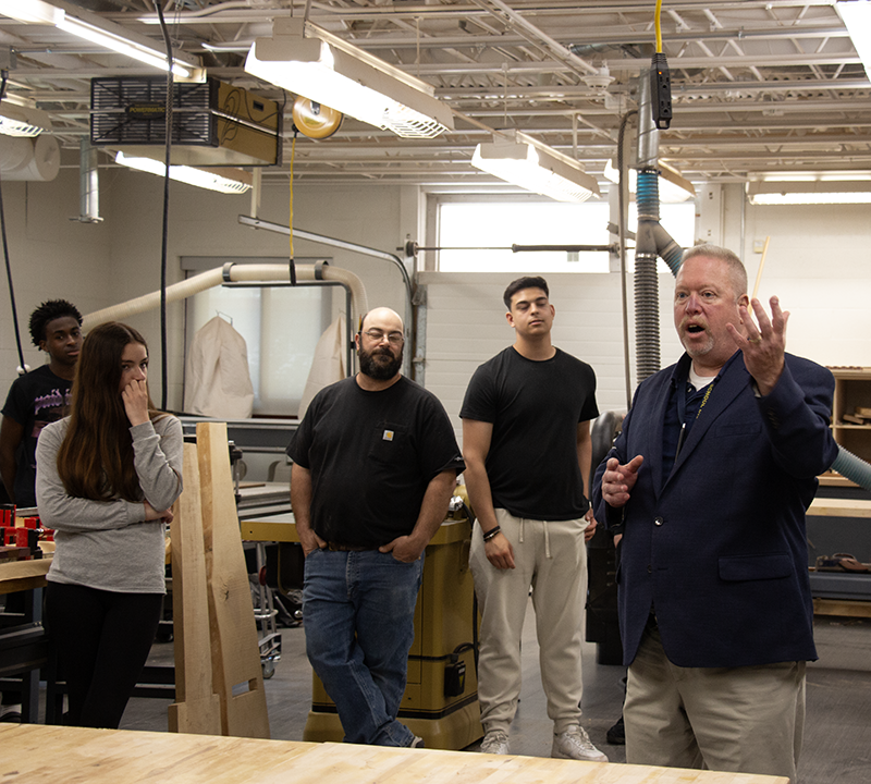 A man on the right has his hand up as he is talking, while three others stand listening.