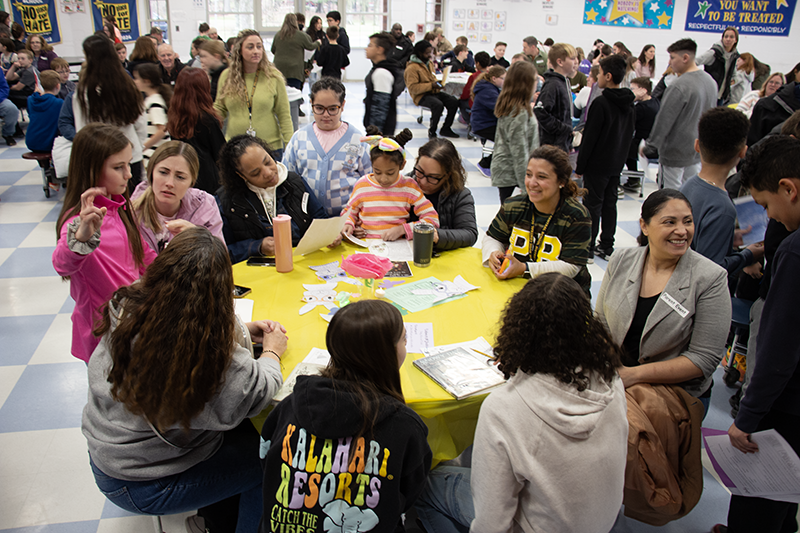 A group of about 10 people work together around a round table.