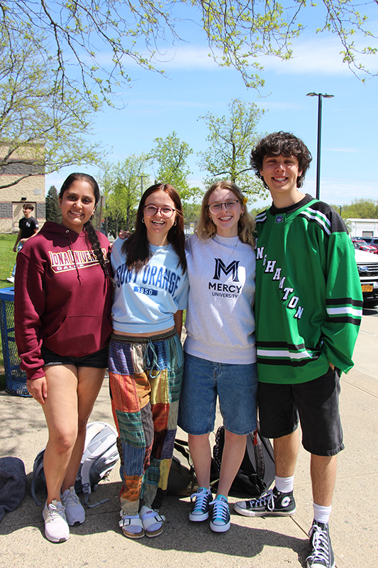 Four high school kids stand together wearing their college shirts