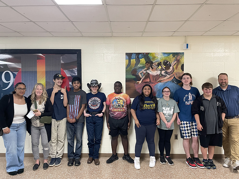 A group of nine high school students and two adults stand smiling.