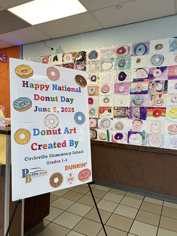 a large sign sayd Happy National Donut Day June 6, 2025 Donut art created by Circleville elementary School. Behind it is a wall filled with donut artwork.