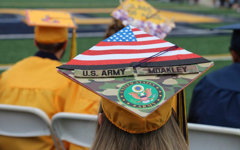 A decorated mortar board with an american flag and camouflage. It says US Army Moakley US Army