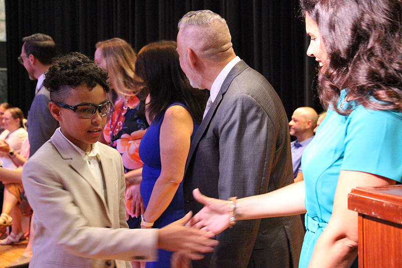 A fifth-grade student shakes hands with a line of adults.