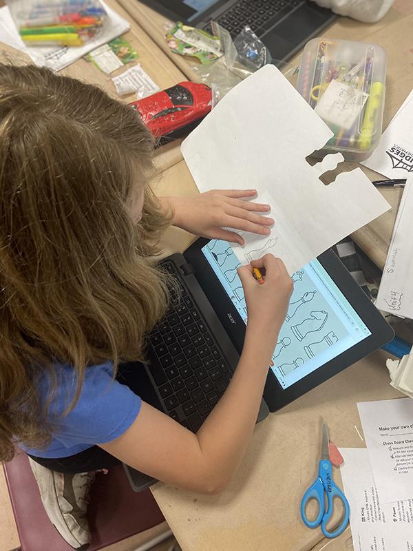 A fourth-grade girl traces chess pieces.