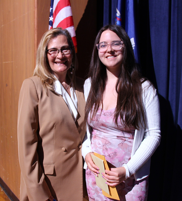 A woman smiles with a high school senior. Both are smiling.