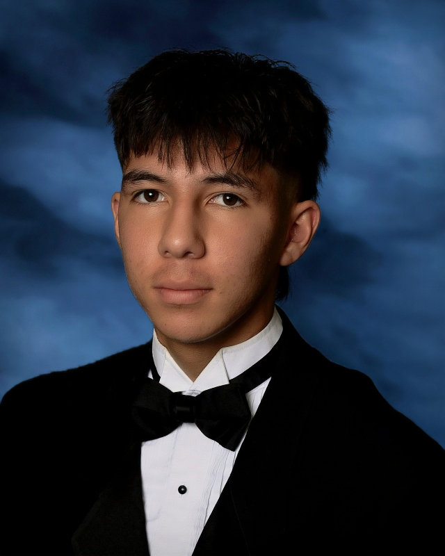 A young man with short dark hair. He is wearing a black tuxedo, white shirt and black bow tie.