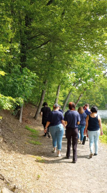 A group of high school kids walk along a path in the woods.