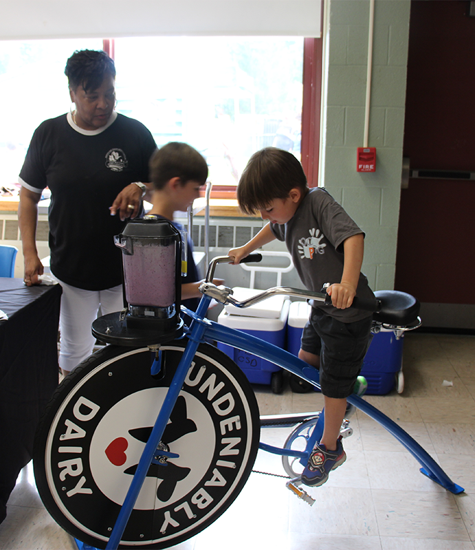 A young boy pedals a bike that is powering a blender.