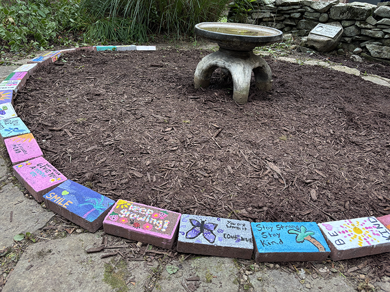 An up-close view of painted bricks in a circle with positive messages on them.