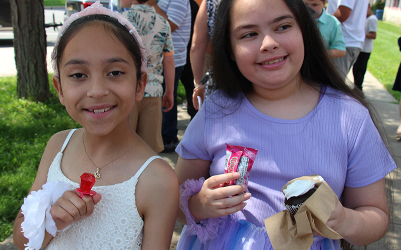 Two fifth-grade girls smile and hold treats.