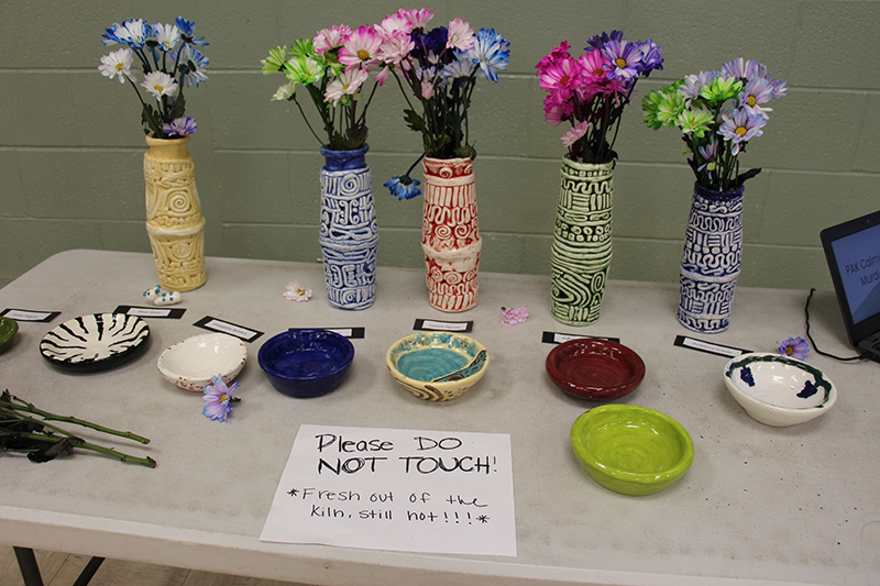 Sitting on a table are clay vases and bowls in many colors and designs, made by students.