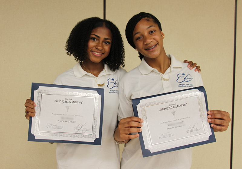 Two high school girls proudly show their certificates after graduation.