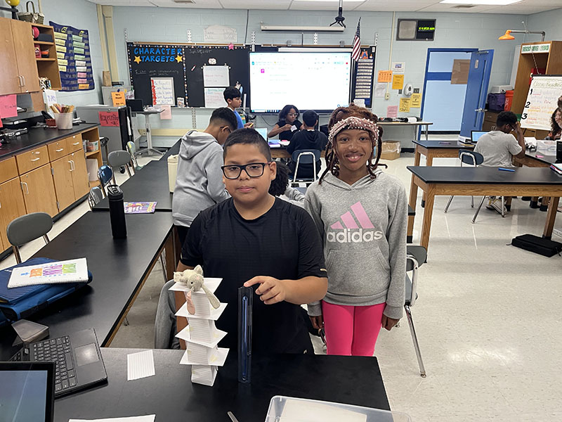Two sixth-grade students stand near the tower made of index cards