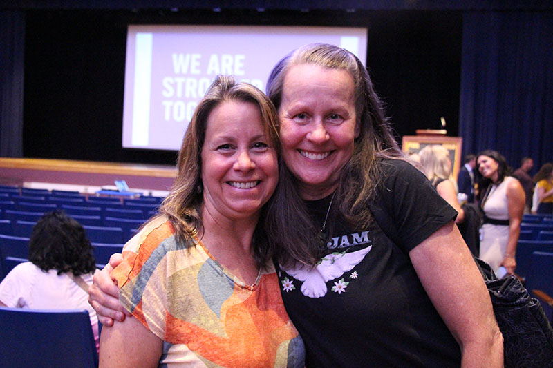 Two women hug each other and smile.