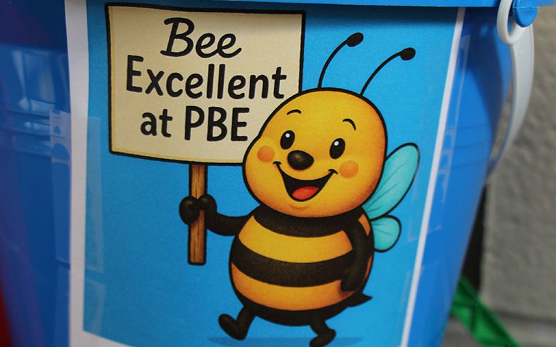 A blue bucket with a sticker on it that says Bee Excellent at PBE