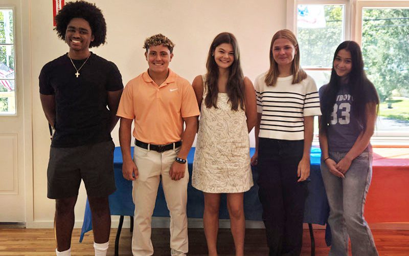 Five high school students, from left, two boys and three girls, stand together and smile.