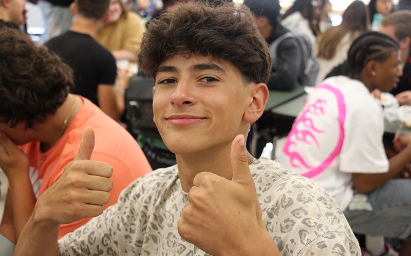 A high school boy gives two thumbs up.