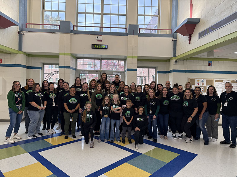 A large grou pof adults, all wearing black and green shirts.