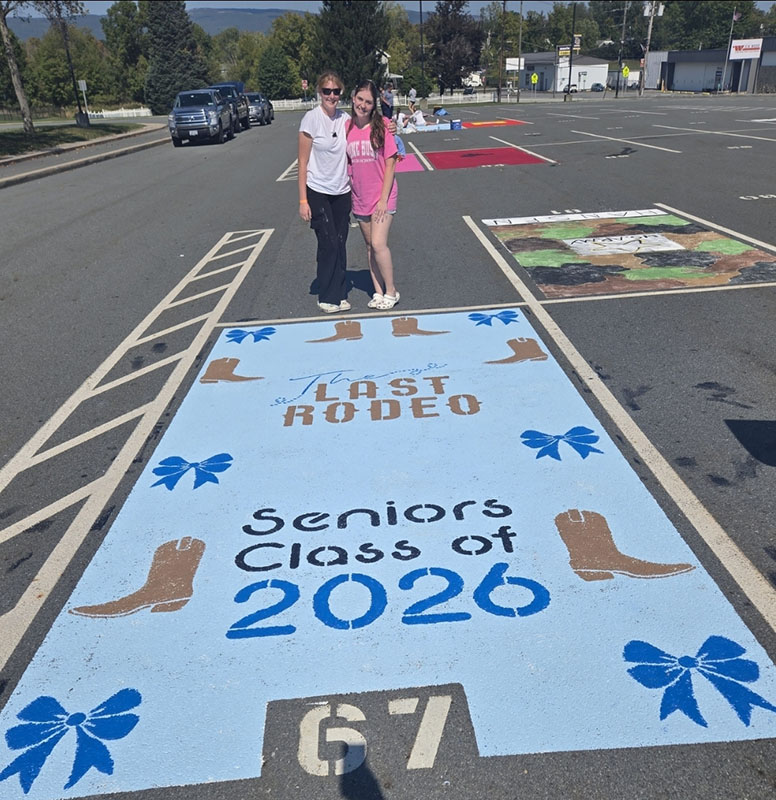High school students in a parking lot. they painted one of the spots a light blue with cowboy boots around it. It says Last Rodeo Seniors Class of 2026