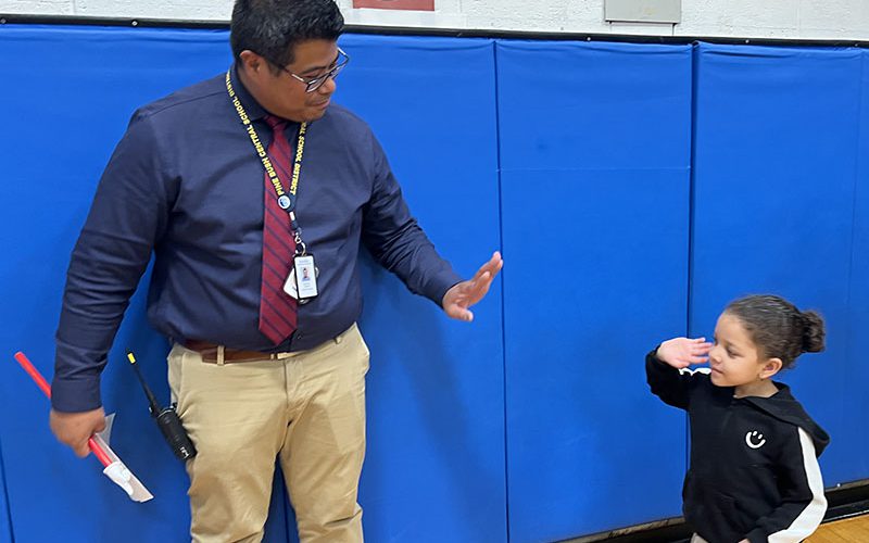 A man in a blue shirt and red tie gives high fives to a little kid.