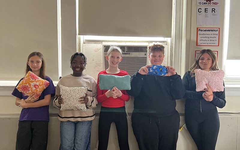 Four middle school students at their lockers with their backs to the camera