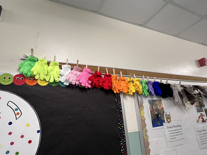 A line of colorful mittens and gloves hang across a wall.