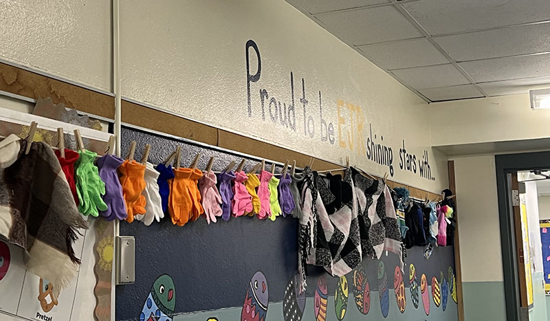 A line of colorful scarves and mittens and hats hang along a wall.
