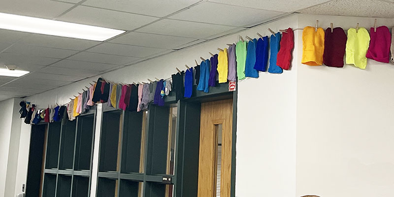 A line of colorful hats hang along a wall outside of an office.