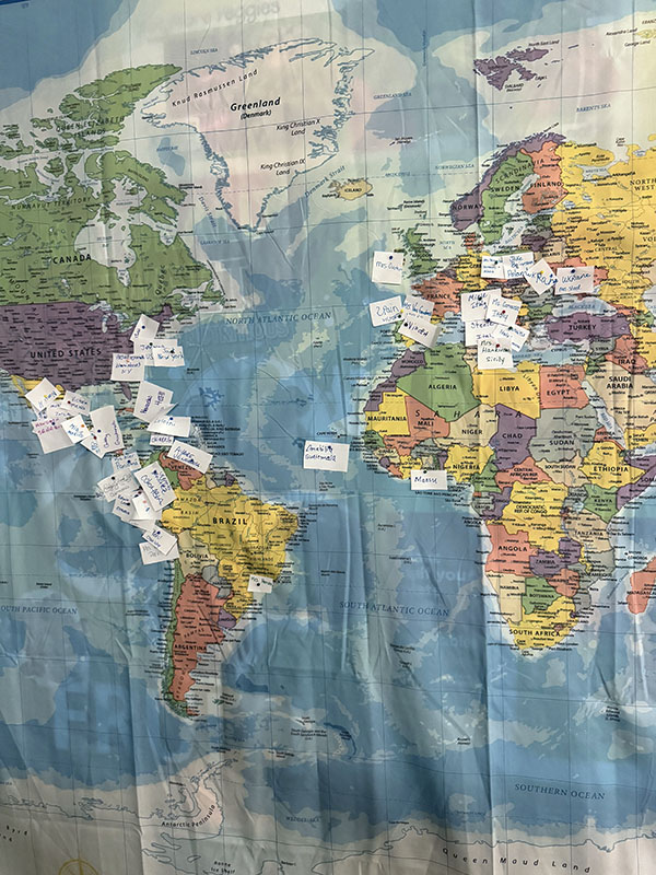 A large wall map with little flags on it to show where people came from.