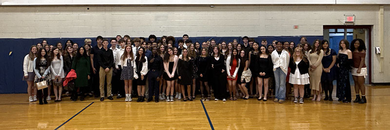 A group of about 100 high school students standing together in a gymnasium.