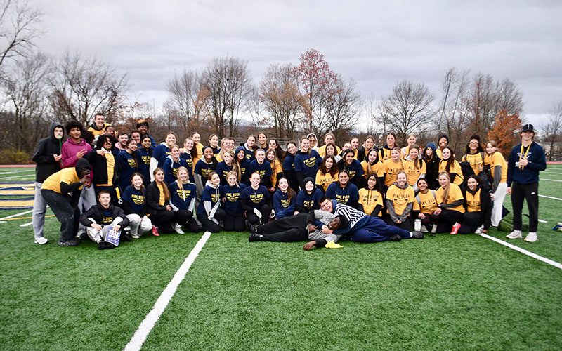 A large grou pof high school juniors and seniors. Mostly girls, on a football field.