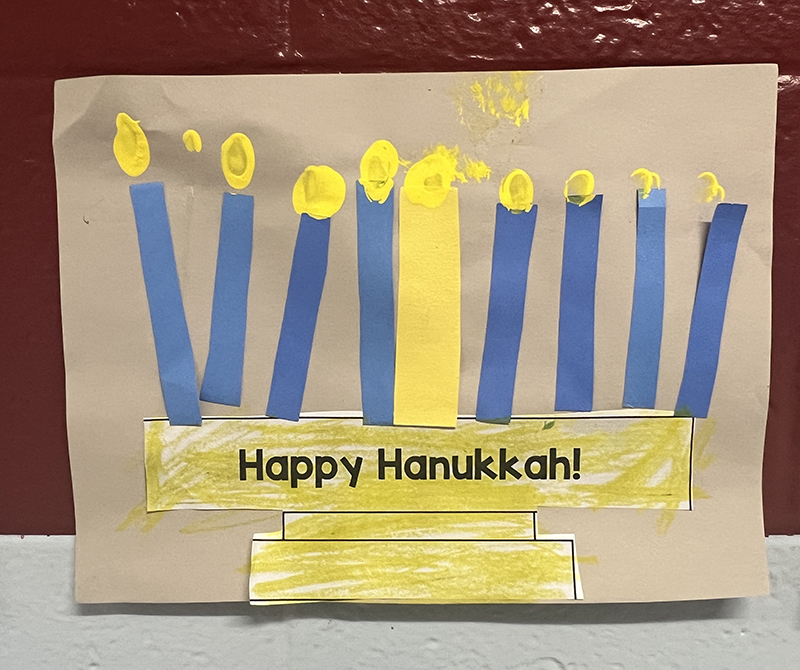 A blue and gold menorah made from paper. It says Happy hanukkah.