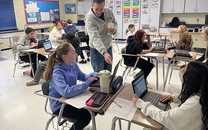 Four middle school students at their lockers with their backs to the camera
