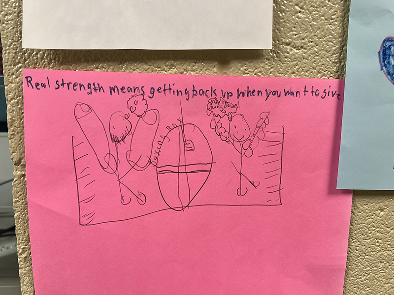 A pink piece of paper with a drawing on it. It says.