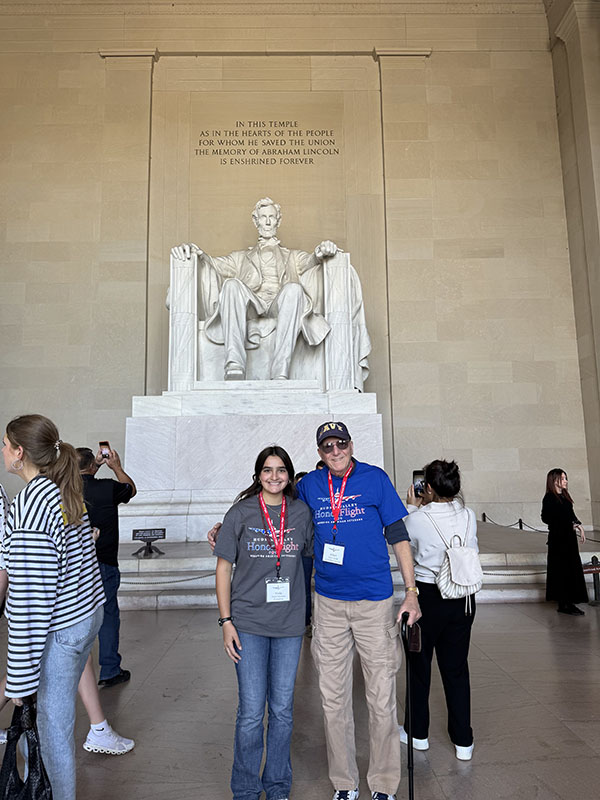 A young woman and an older man stand in front of the Lincoln Memorial