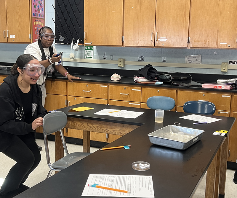 middle school students stand back waiting for their science experiment to pop.
