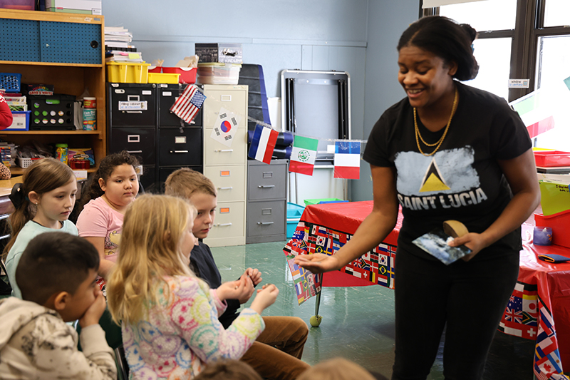 A woman shows a group of elementary kids the coins from St. Lucia.
