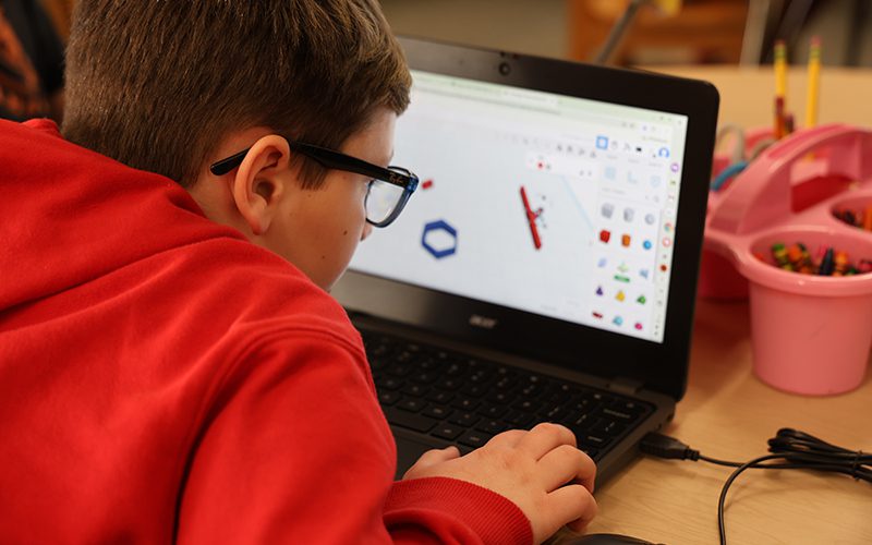 A woman holds a large globe showing a class of children