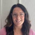 A woman with long dark hair and glasses smiles.