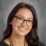 A woman with long dark hair and glasses smiles.