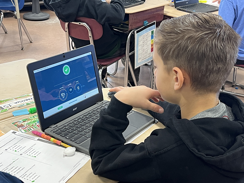 A fourth-grade boy sits at a Chromebook and sees his typing accuracy score is 92.