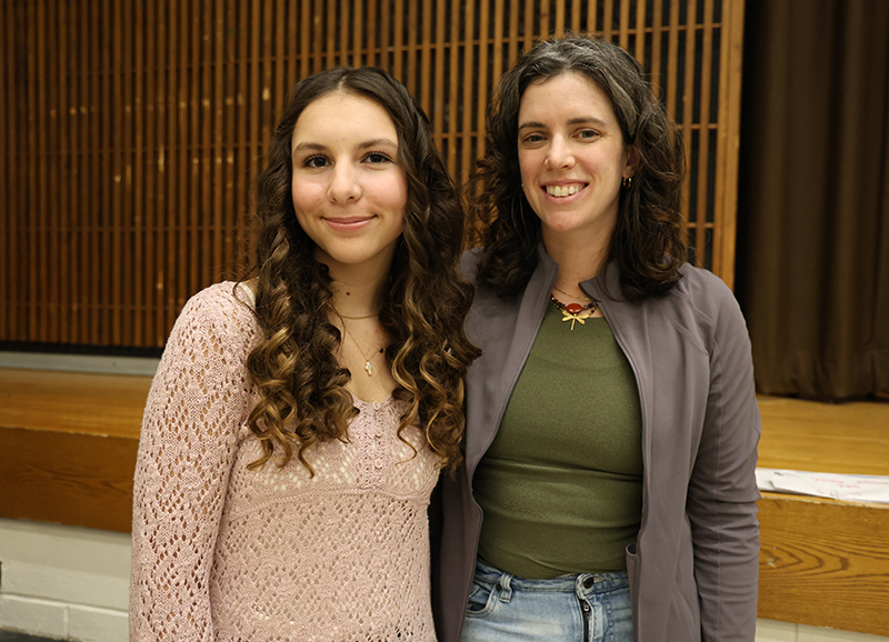 A woman and a high school girl stand together smiling.